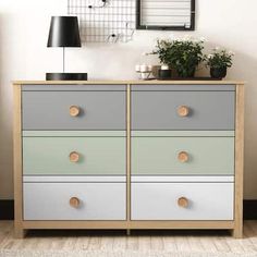 a white and grey dresser sitting next to a lamp