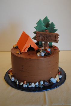 a chocolate cake decorated with an orange tent and camp sign on it's side