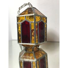 an old stained glass lantern is sitting on a white surface with a chain hanging from it