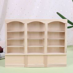 a wooden bookcase with three shelves on the bottom and one shelf below it, sitting on a green surface