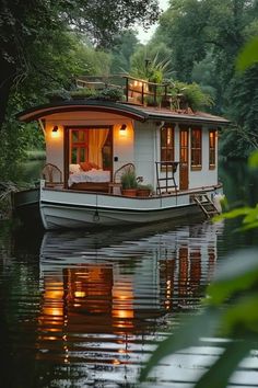 a houseboat floating on top of a lake surrounded by trees and greenery at night