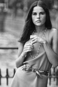 black and white photograph of a woman in dress holding a cup with both hands on her chest