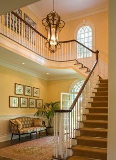 a staircase leading up to a living room with a couch and chandelier on the second floor