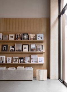 a book shelf filled with books next to a window and a wall mounted display case