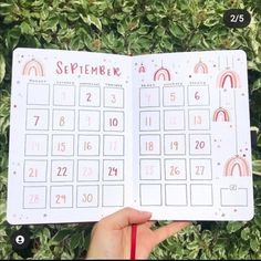 someone holding up a calendar in front of some bushes and trees with the word september written on it