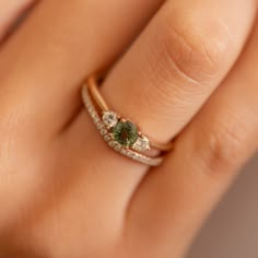 a woman's hand with a ring on it and a green stone in the middle