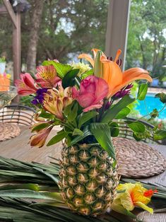 a pineapple vase filled with colorful flowers on top of a table next to a pool