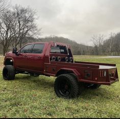 a red pick up truck parked on top of a lush green field