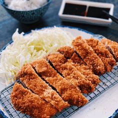 some food on a blue and white plate with chopsticks next to it in a bowl