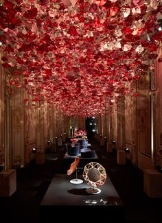 a room filled with lots of red paper flowers hanging from the ceiling and lights on the walls