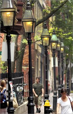 two people walking down the street next to lamps