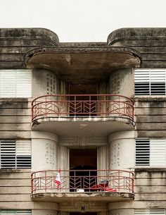 an apartment building with two balconies and red railings on the top floor