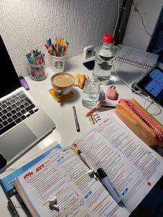 an open book sitting on top of a desk next to a laptop computer and other office supplies