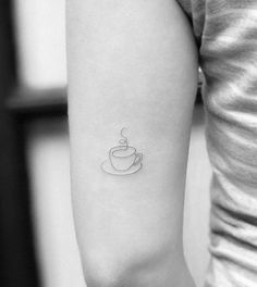 a woman's arm with a coffee cup tattoo on the left side of her arm