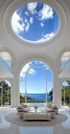 a large living room with high ceilings and an ocean view from the couch to the ceiling