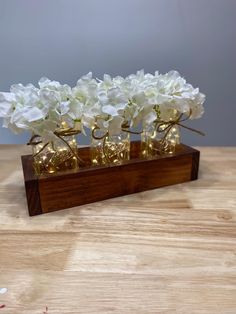 some white flowers are in small vases on a wooden stand with string lights around them