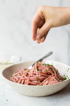 someone is sprinkling parsley on top of a pasta dish