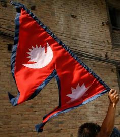 a man holding up a flag in front of a brick building