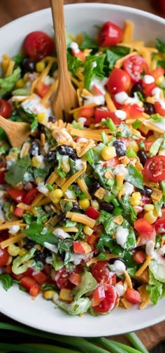 a salad in a white bowl with wooden spoons