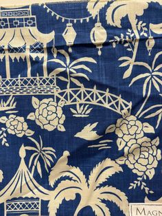 a blue and white fabric with flowers, trees, and other things in the background