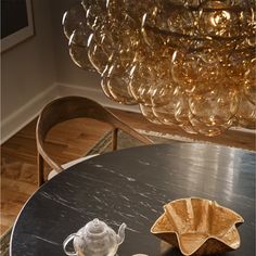 a glass chandelier hanging from the ceiling above a table with two cups on it