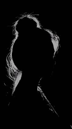 a black and white photo of a woman's face with long hair in the dark