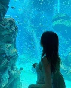 a woman looking at fish in an aquarium