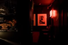 a dimly lit hallway with posters on the wall and lights in the dark behind it