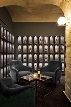 a dimly lit room with two chairs and a coffee table in front of the wall