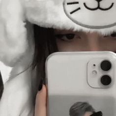 a person holding up a cell phone with a cat hat on top of their head