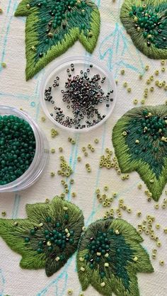 some beads are laying on top of green leaves and sprinkles in a bowl