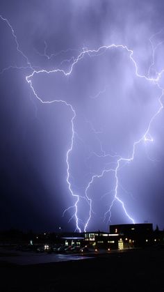 a lightning storm is seen in the sky over a building and parking lot at night