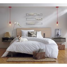 a dog laying on top of a white bed in a room with wooden flooring