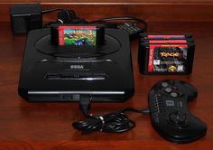 a video game system sitting on top of a wooden table next to a controller and two games