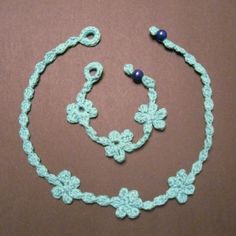 a crocheted necklace and earring set on a brown surface with blue beads