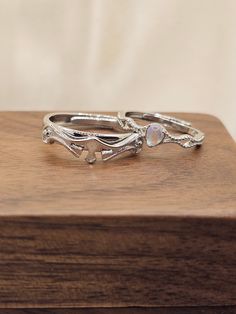 two silver rings sitting on top of a wooden box