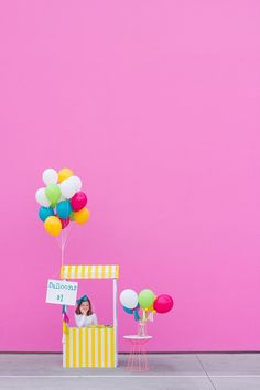 a small cart with balloons and a sign on it