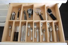 an open drawer with utensils and spoons in it