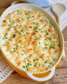 a casserole dish with cheese and scallions in it on a wooden table