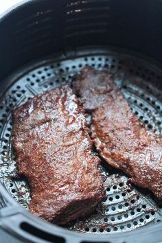 two steaks are cooking in an air fryer