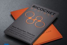 an orange and black business card on top of a gray surface with the words ricochet designs