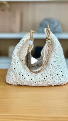 a white crocheted purse sitting on top of a wooden table next to a vase