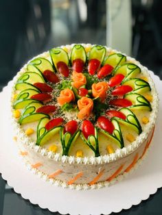 a cake decorated with cucumbers and peppers on a white plate sitting on a table