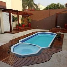 an empty swimming pool in the middle of a backyard with wooden decking and steps leading up to it