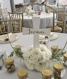 a white table topped with lots of flowers next to jars filled with candles and saucers