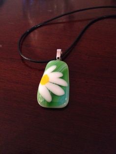 a green and white flower pendant sitting on top of a wooden table