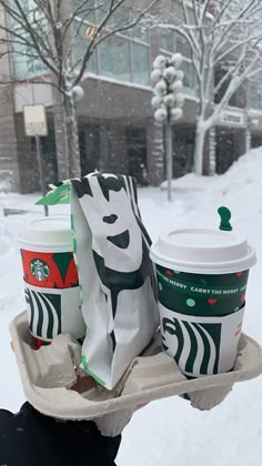 starbucks coffees are sitting on a tray in the snow