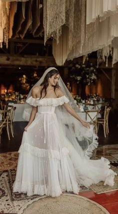 a woman wearing a wedding dress and veil standing in front of a chandelier