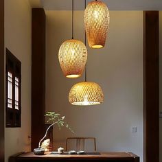 three lights hanging from the ceiling above a table with a potted plant on it