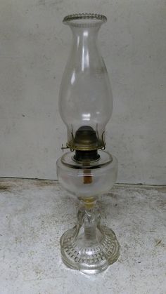 an old fashioned oil lamp sitting on top of a white tablecloth covered floor next to a wall